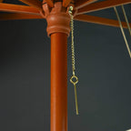 Close-up of wooden parasol pole with chain and hanging rope detail under dark canopy
