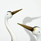 Close-up steel crane ornament with white face and long golden beak, blue feather body