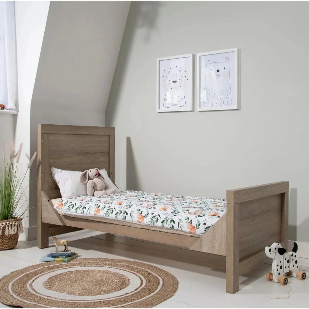 Light oak toddler bed with side rails and floral bedding