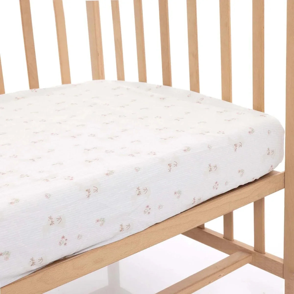 White baby fitted sheet on a crib, featuring small pastel floral print