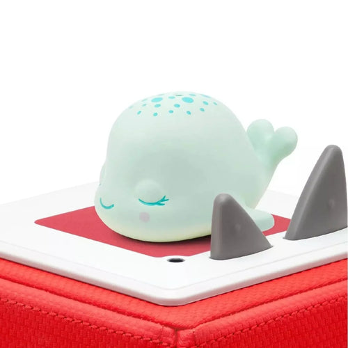 Sleepy whale audio figure resting on a white base with dark gray ear pieces