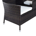 Corner view of dark brown woven rattan loveseat with white seat cushions and metal feet