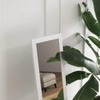 White wall hanging full-length mirror with rectangular frame mounted on a wall