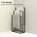 Black 3-bar towel rack with thick gray towels hanging over the bars.