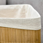 Close-up of white fabric lining top edge on bamboo laundry hamper.