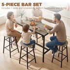 Grey bar table set with four round stools and black frames, used for dining in a home