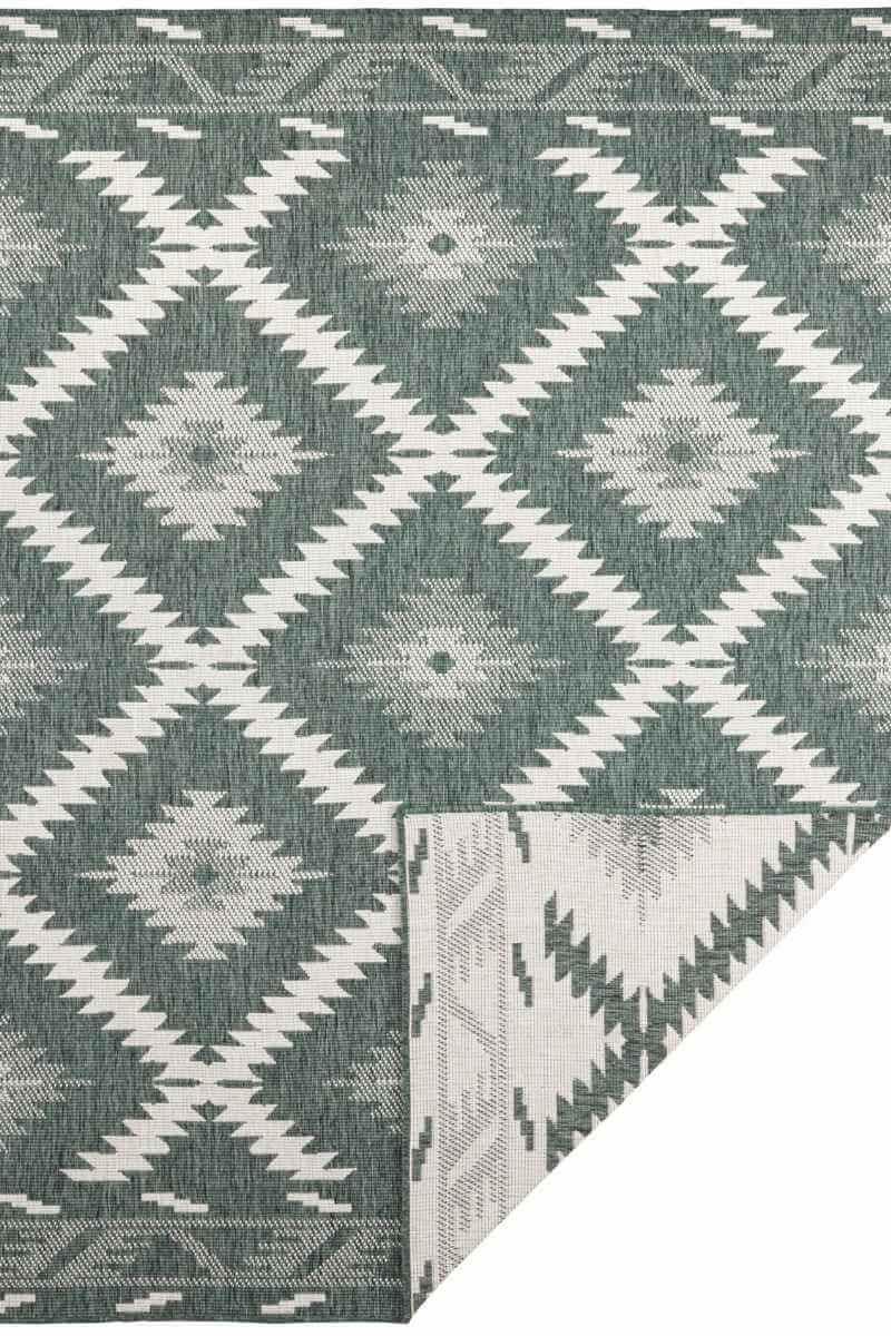 Indoor-outdoor rug with green and gray diamond pattern on light background, corner fold visible