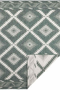 Indoor-outdoor rug with green and gray diamond pattern on light background, corner fold visible