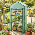 Green mesh three-tier mini greenhouse with wire shelves and potted plants inside