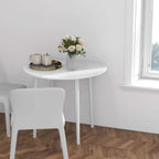 Small white round dining table with flowers and decor on top, four straight legs.