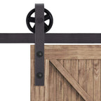 Barn door roller bracket with round wheel on dark track, mounted to wood door