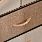Close-up of a fabric drawer front with wooden pull handle on a steel-framed dresser tower