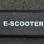 Textured black electric scooter deck with anti-slip surface and E-SCOOTER lettering