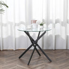 Round clear glass dining table with black crossed metal legs and minimal modern design