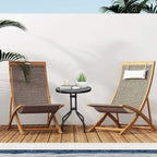 Black round bistro table with tempered glass top and metal tripod legs in outdoor patio.