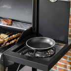 Black gas grill with side burner and skillet on the side shelf