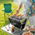Portable charcoal grill with open lid and cooking grate, grilling kebabs on coals