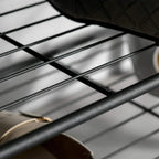 Close-up of black wire grid shelves on the shoe bench