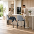Two grey velvet bar stools with backrest and footrest, black metal legs