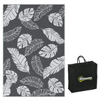 Reversible outdoor rug with grey-and-white leaf pattern, shown with black carry bag