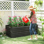 Black outdoor raised bed planter filled with flowers, with watering can being used