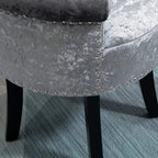 Grey upholstered side panel with studded nailhead trim on vanity stool, black legs