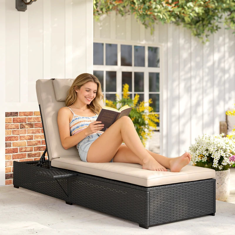 Black rattan reclining sun lounger with beige cushion, used for reading