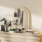 Beige arched wall mirror with textured grooved frame on a decorative shelf