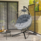 Grey hanging rattan swing chair with quilted cushion and black metal tripod stand