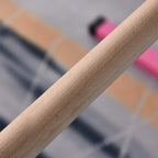 Close-up of light wood grip on a pink kids gymnastics horizontal bar