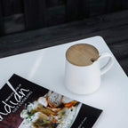 White square outdoor table with mug and magazine on textured grid tabletop
