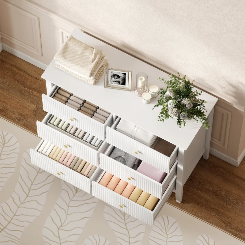 White fluted dresser with open drawers revealing compartments for folded items