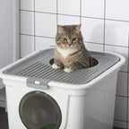 Cat sitting on the grated top tray of a white enclosed litter box