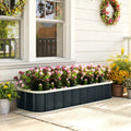Dark grey raised garden bed with pink and yellow flowers beside a home walkway