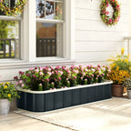 Dark grey raised garden bed with pink and yellow flowers beside a home walkway