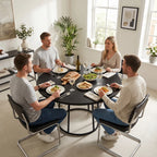 Round black dining table with central conical metal base surrounded by chairs