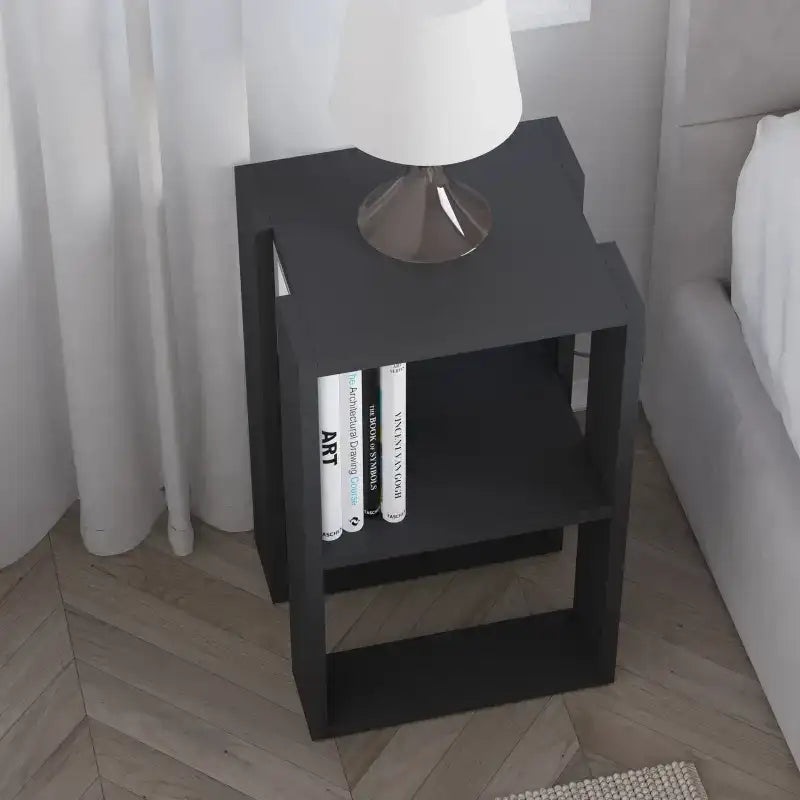 Modern bedside table with open shelves, black finish, holds books under lamp base