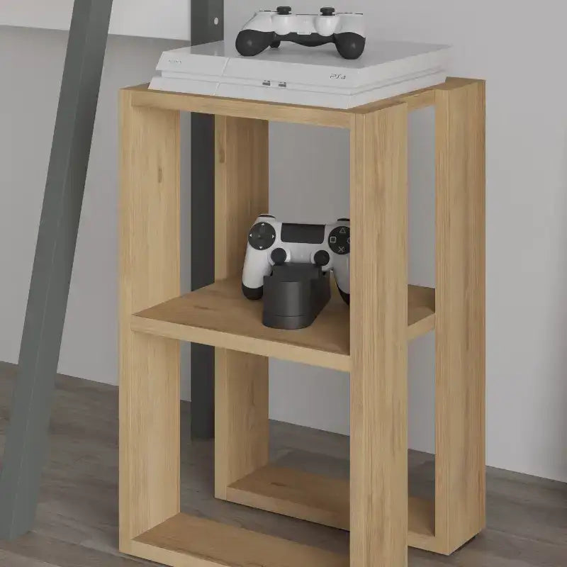 Light oak bedside table with open front shelves holding small gaming items.