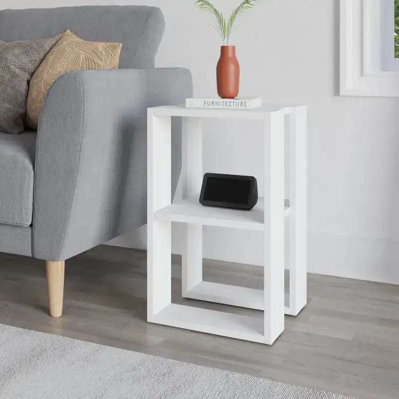 Modern bedside table with white open frame and shelf, styled with a black device