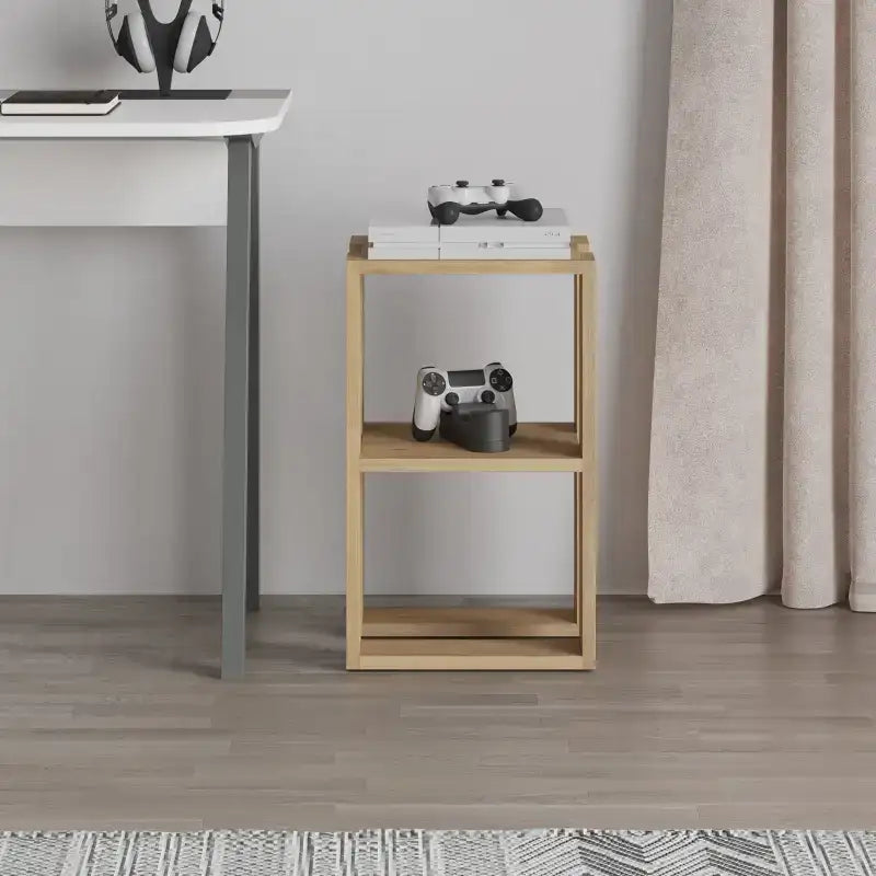 Light oak bedside table with open shelves and top surface, holding a controller and mug.