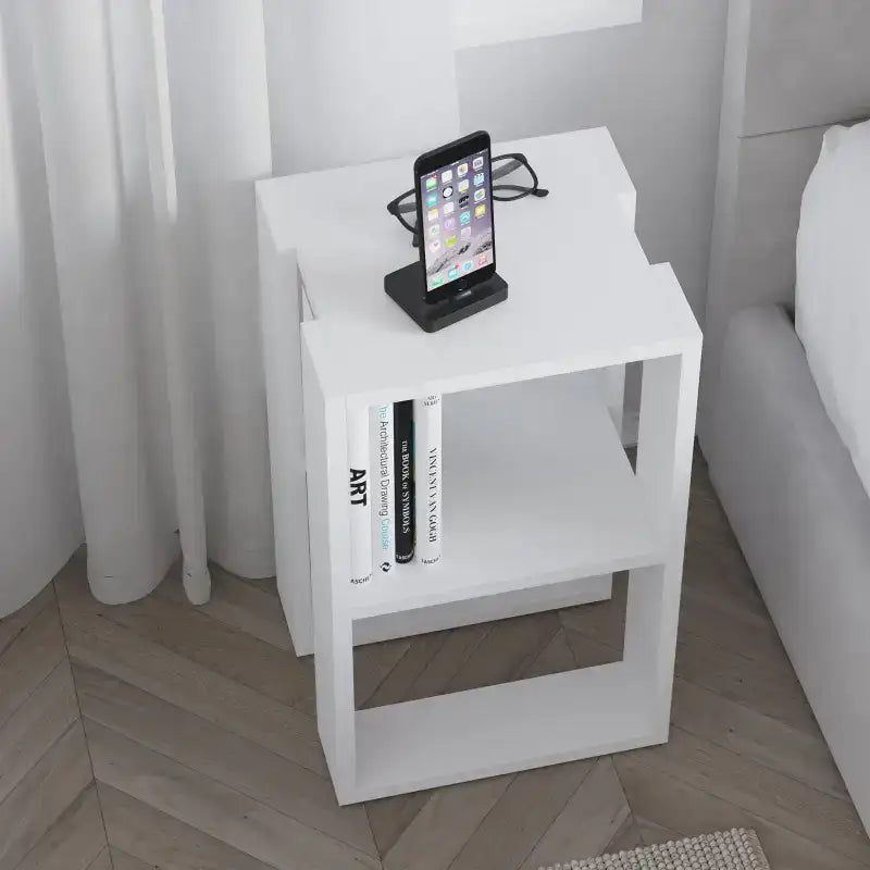 White bedside table with two open shelves; tabletop holds a tablet and books