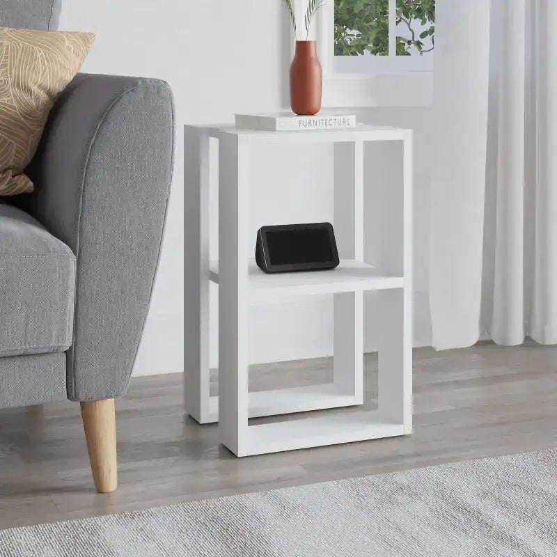 White modern bedside table with open shelves, tabletop for a black device and vase