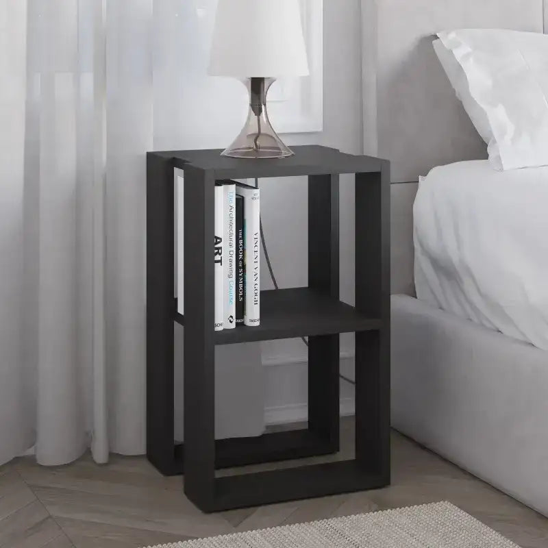 Modern bedside table with open shelves and dark finish, holding books and alarm clock