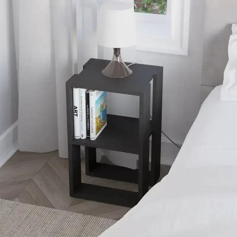 Black modern bedside table with open shelves, lamp base and books on lower tier