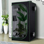 Black grow tent with open door, reflective lining, ventilation port, and indoor plants