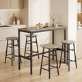 Grey wood-effect bar table with four round stools, black frames in a kitchen setting