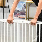 White wooden dog gate top rail with hands adjusting the latch