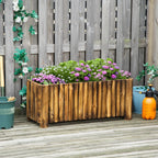 Wooden raised garden bed planter filled with purple flowers against a wooden fence.