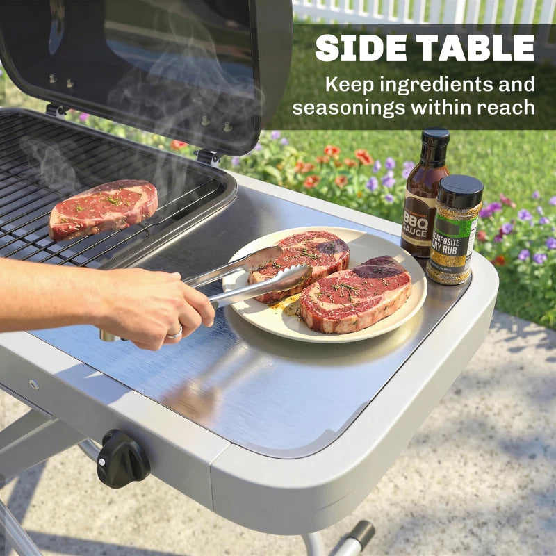 Gas grill side table with utensils and steak ready to cook, black lid open
