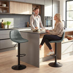 Green swivel bar stool with curved upholstered seat, footrest ring, and round base